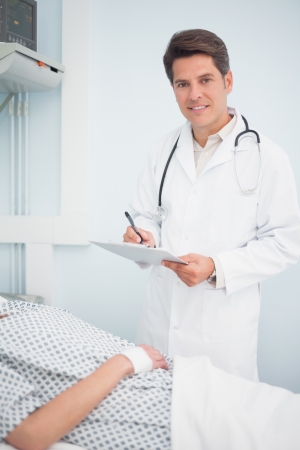 Doctor writing on his chart in hospital wardの写真素材