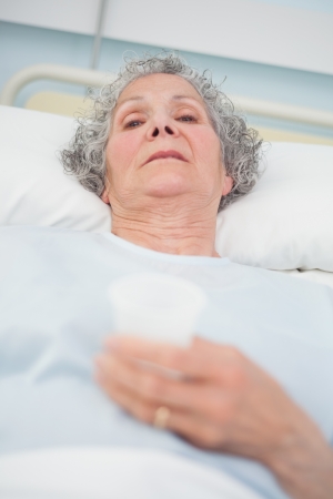 Elderly patient looking at camera in hospital wardの写真素材