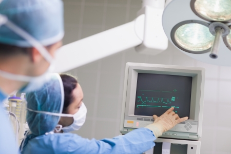 Doctor showing the ECG monitor in operating theaterの写真素材