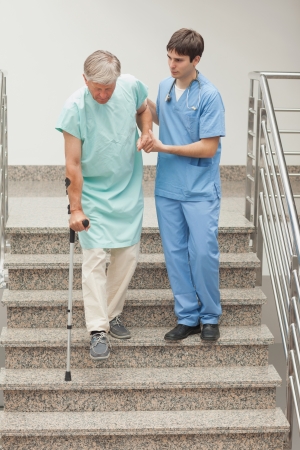 Male nurse assisting a patient on stairs in hospital の写真素材