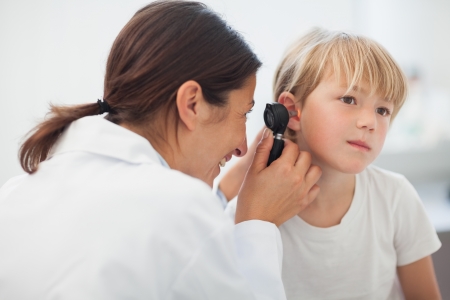 Doctor auscultating the ear of a child in examination roomの写真素材