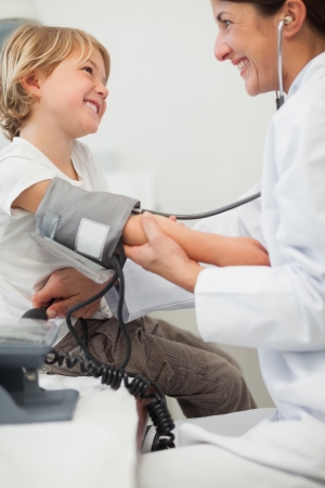Doctor examining blood pressure of a child in examination roomの写真素材