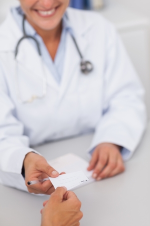 Doctor giving a paper in a medical officeの写真素材