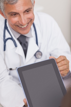 Doctor holding a tablet computer while smiling in medical officeの写真素材