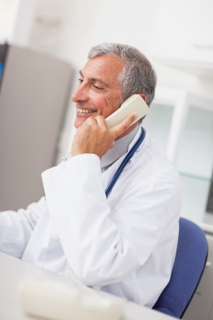 Smiling doctor calling in medical officeの写真素材