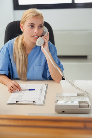 Female nurse holding a phone in hospital receptionの写真素材