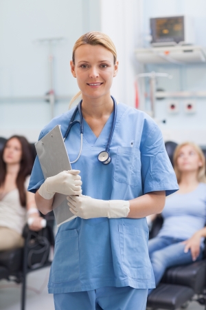 Nurse standing while holding a clipboard in hospital wardの写真素材