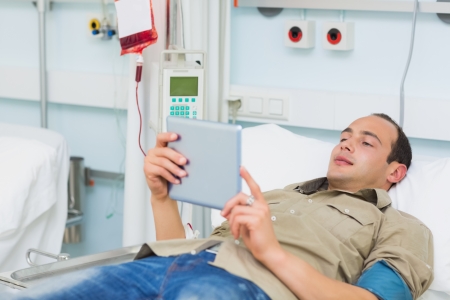 Transfused patient using a tablet computer in hospital wardの写真素材