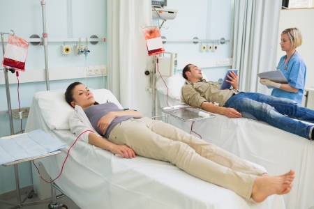 Two transfused patients lying on a medical bed in hospital wardの写真素材