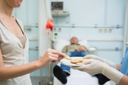 Nurse giving biscuits to a donor in hospital wardの写真素材