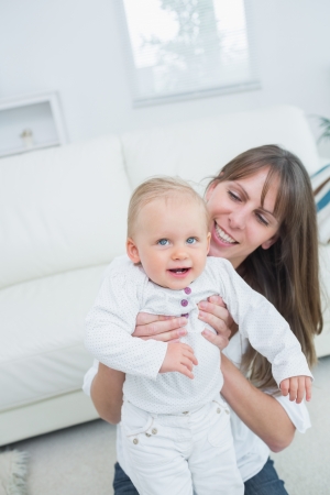 Mother holding a baby in living roomの写真素材