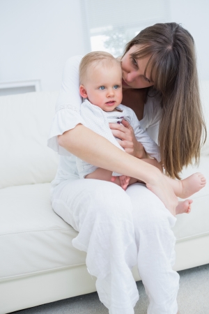 Baby sitting on his mother knees in living roomの写真素材
