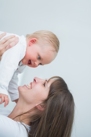 Smiling mother holding her baby in living roomの写真素材