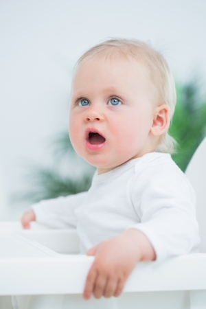 Baby sitting on a high chair in living roomの写真素材