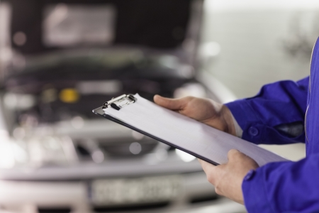 Close up of a man holding a clipboard in a garageの写真素材