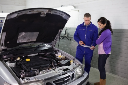 Mechanic holding a clipboard next to a woman in a garageの写真素材