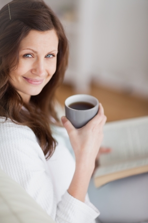 Woman holding a coffee mug in a living roomの写真素材