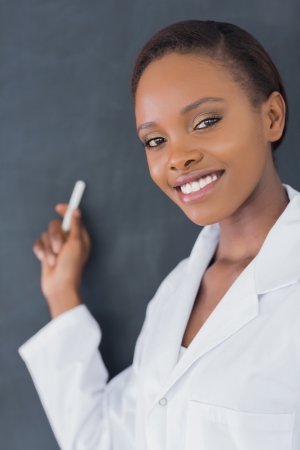 Close up of a teacher smiling while holding a chalk in a classroomの写真素材