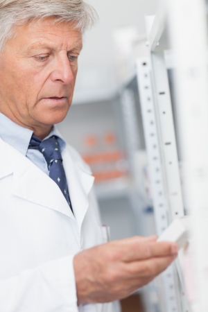 Pharmacist looking at pills in a shelf in a hospitalの写真素材