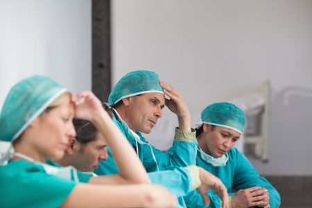 Group of sad surgeons sitting on the floor in a hospitalの写真素材