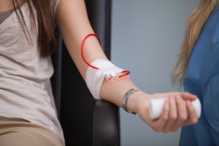 Young woman giving her blood in hospital wardの写真素材