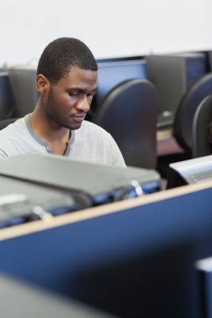 Man sitting at computer desk in computer class in collegeの写真素材
