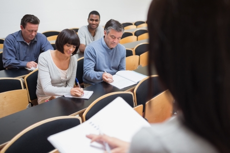 Mature students taking notes in class at collegeの写真素材