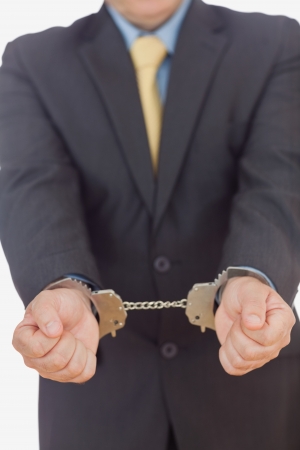 Businessman with handcuffs against white backgroundの写真素材
