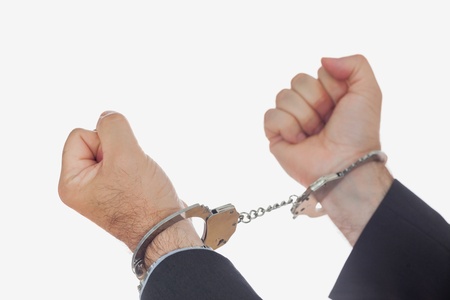 Man in handcuffs clenching fists over white backgroundの写真素材