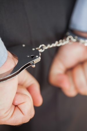 Close-up of businessman with handcuffs clenching fists