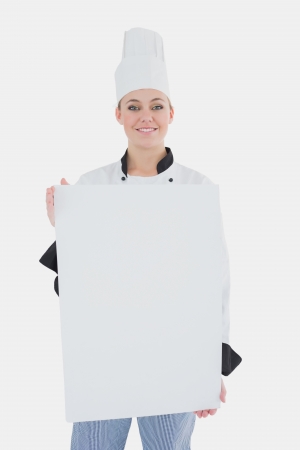 Portrait of happy female chef with blank billboard over white backgroundの写真素材