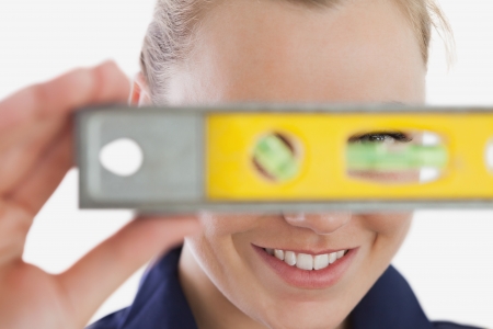Close-up of young female technician holding spirit level over white backgroundの写真素材