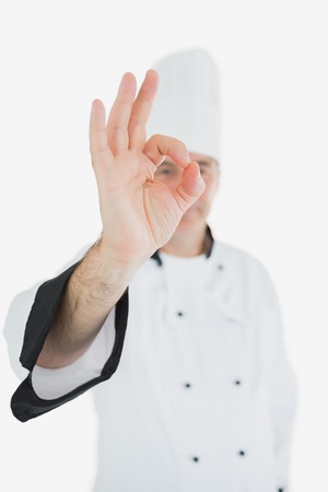 Portrait of mature chef in uniform showing ok sign against white backgroundの写真素材