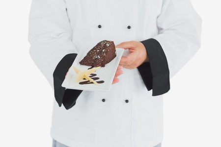 Chef offering garnished chocolate pastry over white backgroundの写真素材