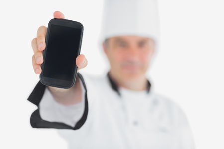 Male chef displaying smartphone against white backgroundの写真素材