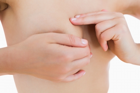 Nude young woman touching her breast over white backgroundの写真素材