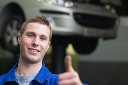 Portrait of car mechanic gesturing thumbs up in workshopの写真素材