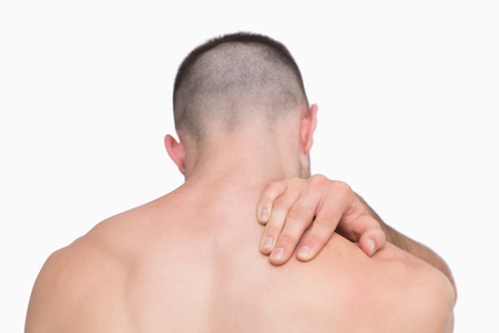 Rear view of shirtless man with neck pain over white background