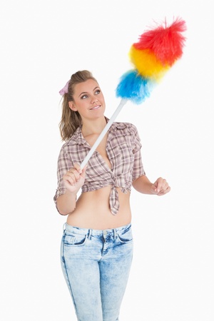 Casual young woman using colorful feather duster over white backgroundの写真素材