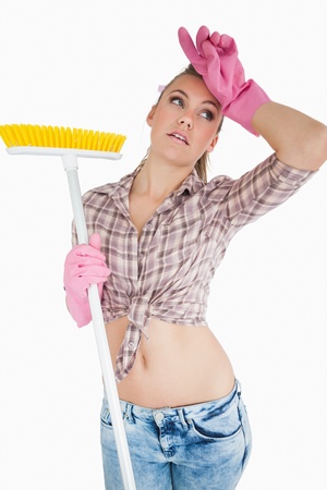 Tired young woman holding broom over white backgroundの写真素材
