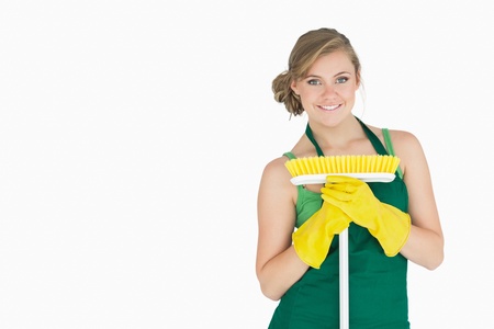 Portrait of young woman with broom over white backgroundの写真素材