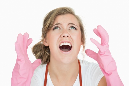 Close-up of young maid in pink gloves screaming over white backgroundの写真素材