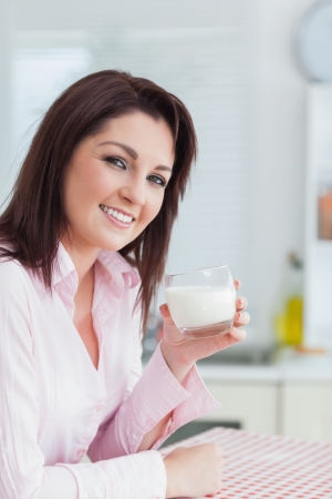 Portrait of young woman with glass of milk in the kitchenの写真素材