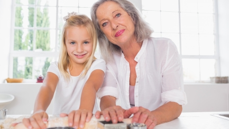 Granddaughter making biscuits with her grandmother in the kitchen