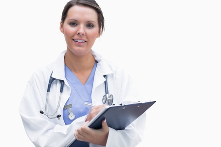Portrait of smiling female doctor with clipboard over white backgroundの写真素材