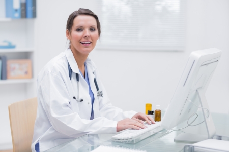 Portrait of smiling young female doctor using computer at clinicの写真素材