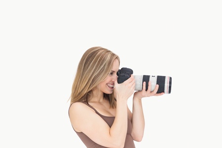 Side view of happy female photographer with photographic camera over white background