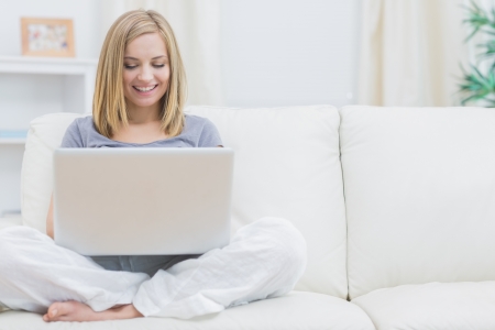 Relaxed happy young woman using laptop on sofa at homeの写真素材