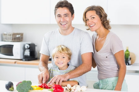 Happy family preparing vegetables together in kitchenの写真素材