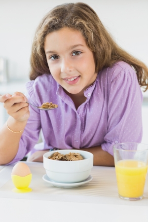 Young girl having cereal for breakfast in kitchenの写真素材
